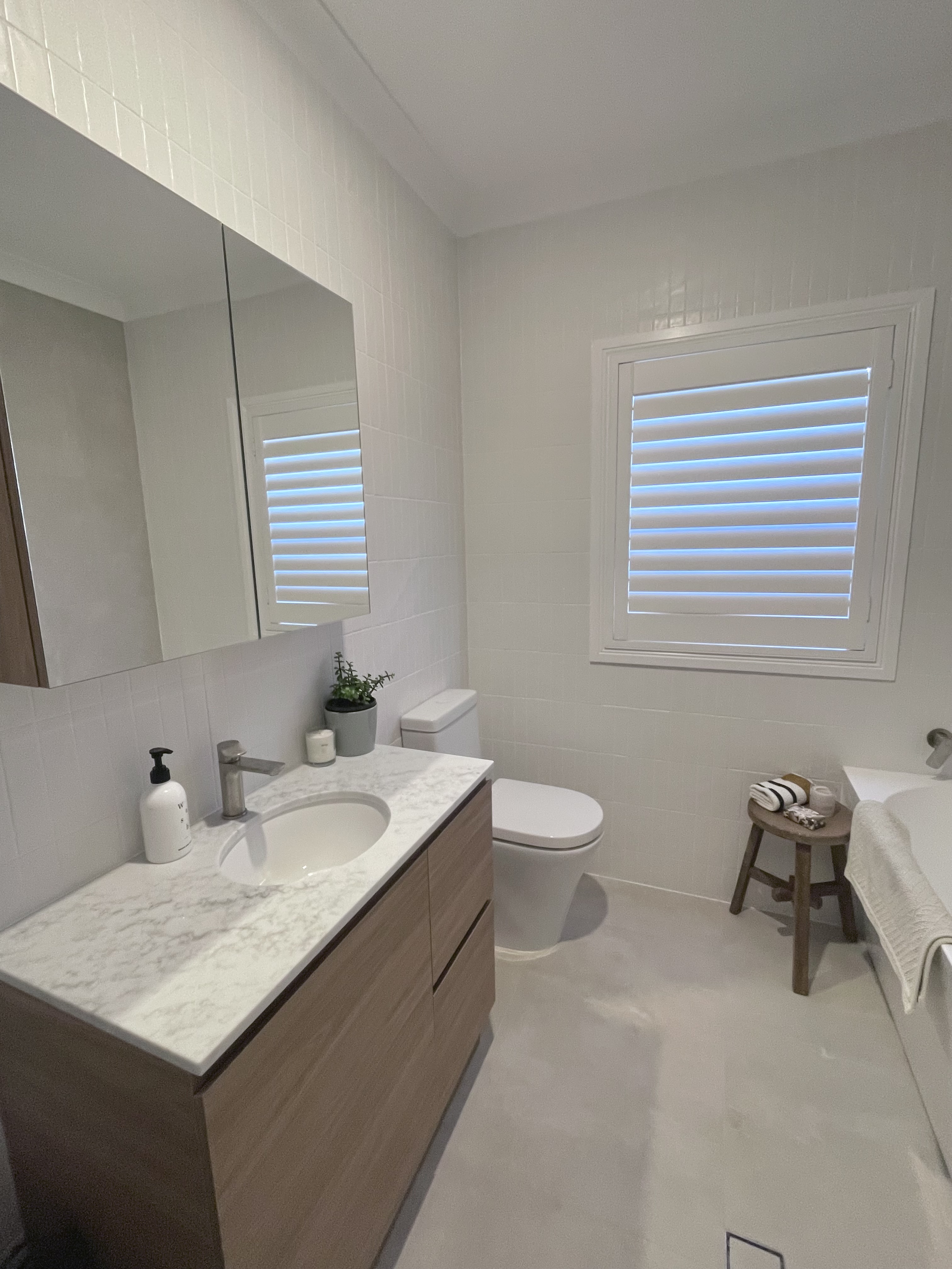 Completed full white tile bathroom with wood vanity