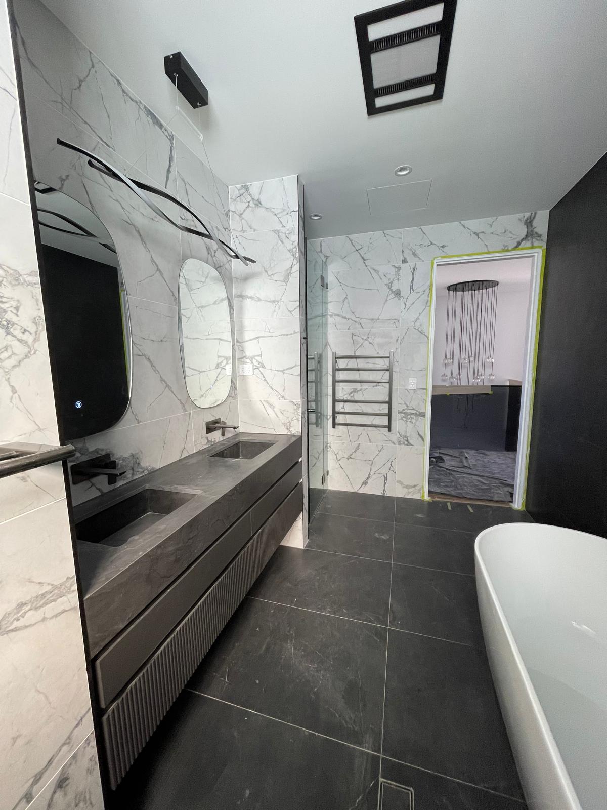 Completed marble main bathroom with double vanity and freestanding bath