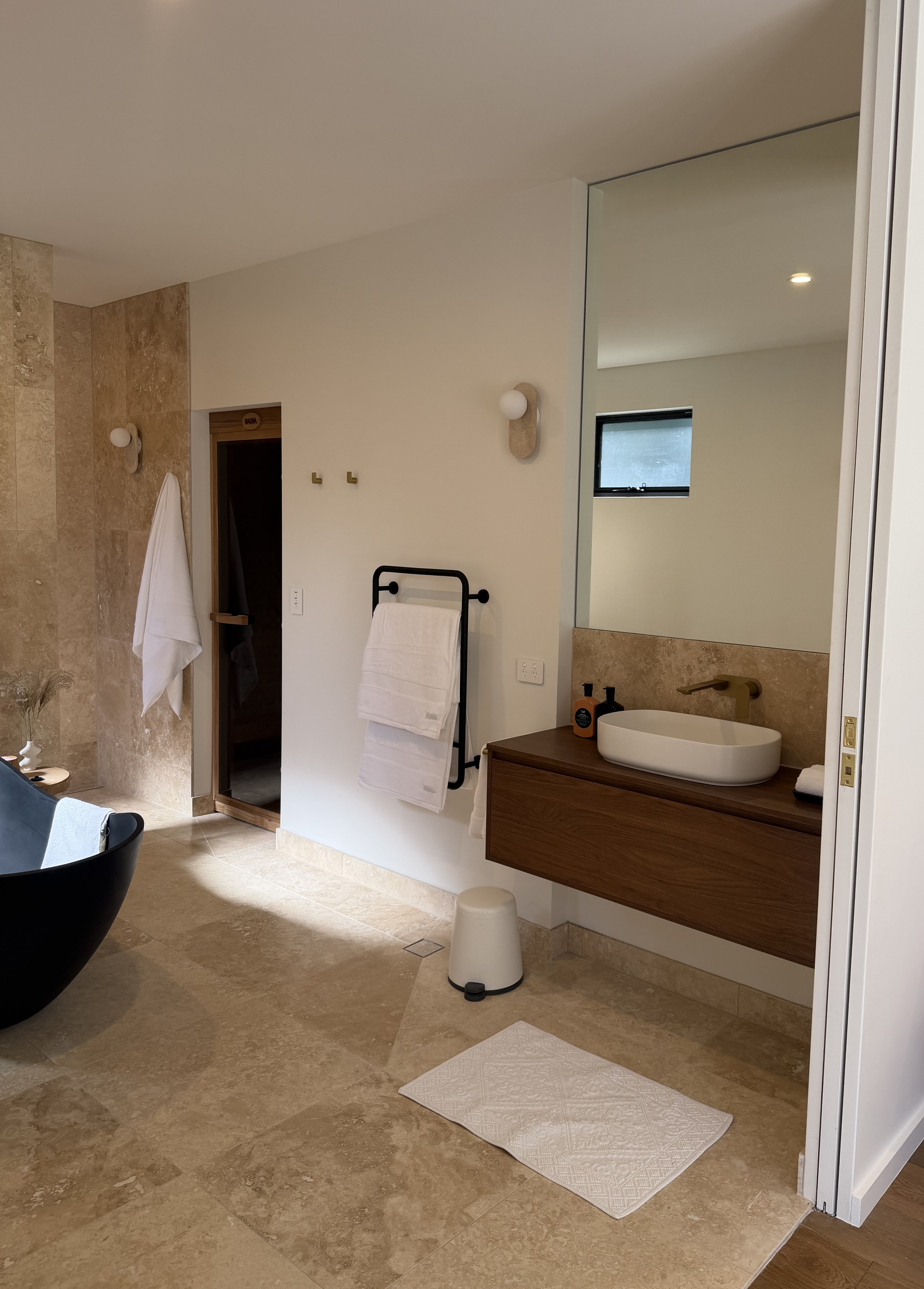 Completed travertine main bathroom with wood vanity