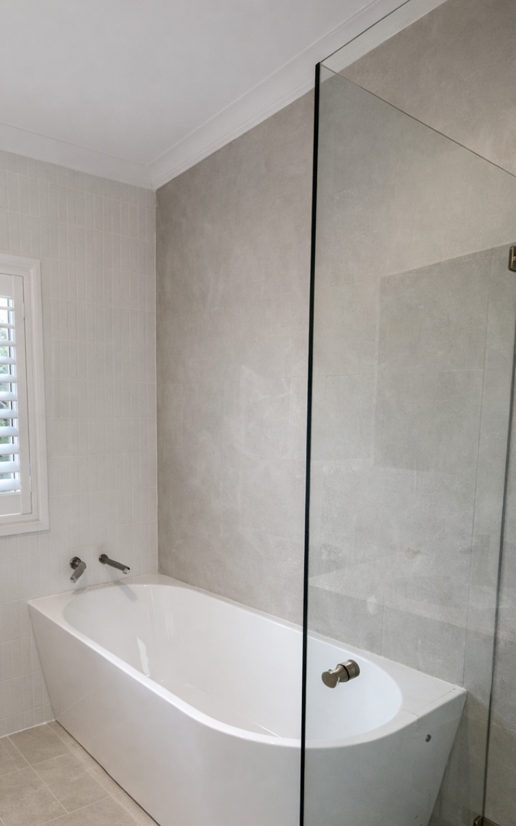 Completed white tile bathroom with bath and shower